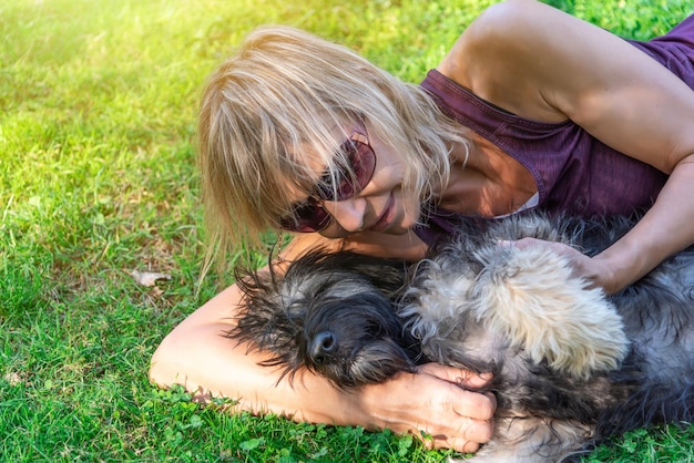 Vrouw liggend op het gras met spelende en knuffelende Catalaanse herdershond Liefde voor huisdieren Adopteer een huisdier