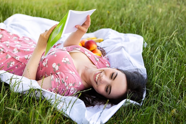 Vrouw liggend op wit laken vasthouden en boeknotities lezen Dame rust even uit in het stadspark