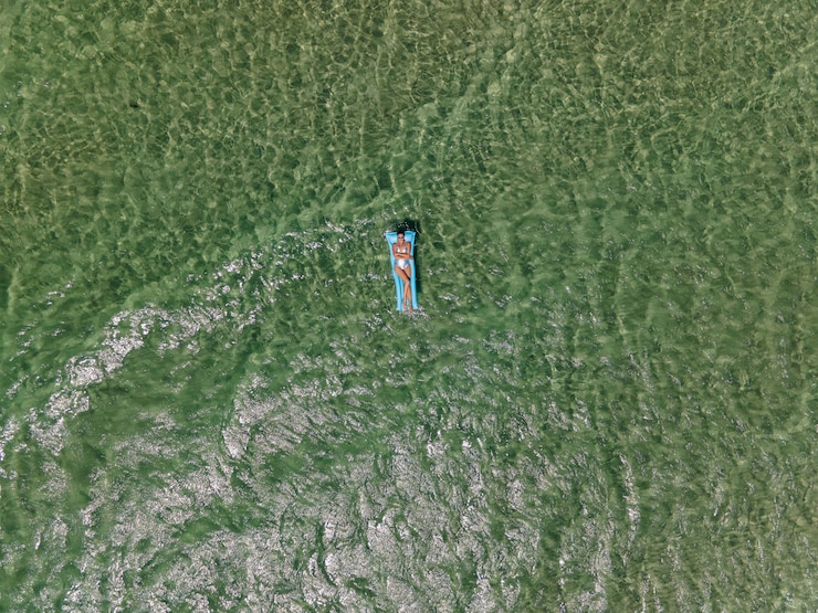 Foto vrouw ligt in een zilveren zwempak op een blauwe opblaasbare matras in de zee