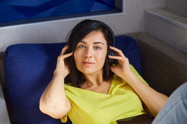 Vrouw ligt op de bank en luistert naar muziek.