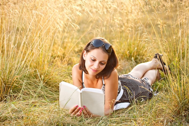 Vrouw ligt op gras en leest boek