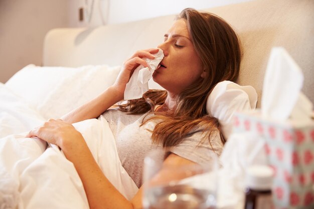 Vrouw lijdt aan kou in bed met weefsel