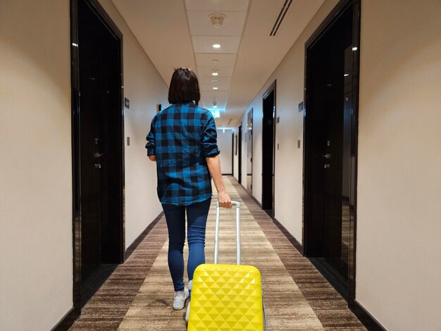 Vrouw loopt door een gang met een gele koffer