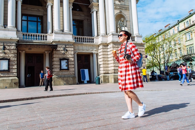 Vrouw loopt door het centrum van de Europese stad met ijs en camera zonnige dag