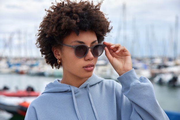 vrouw loopt in de zeehaven tijdens haar vrije tijd draagt een zonnebril en een blauw sweatshirt bewondert het prachtige uitzicht geniet van een weekendtrip op de jachtpier ademt zeelucht