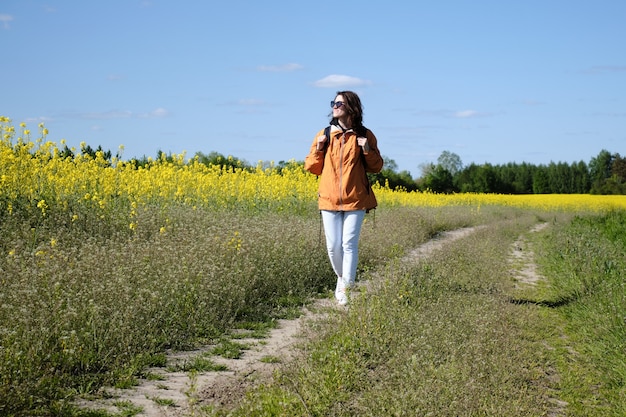 Vrouw loopt langs een landelijke weg langs een weiland met bloemen