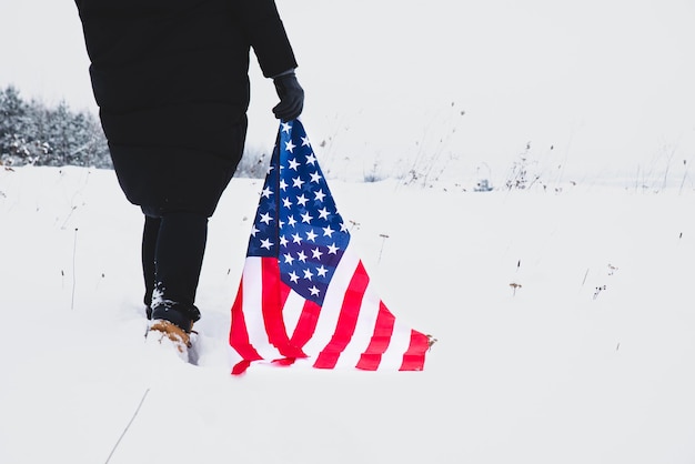 Vrouw loopt langs gesneeuwd ingediend met usa vlag in handen close-up