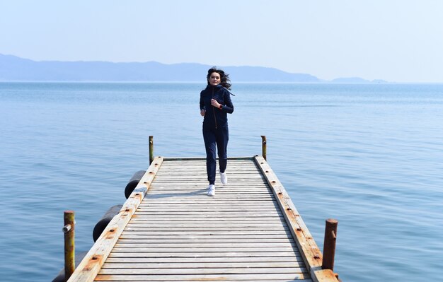 Vrouw loopt op een houten pier door de Japanse zee