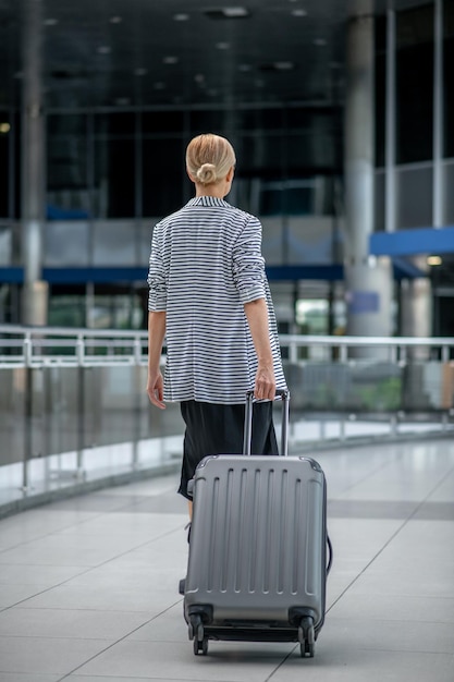 Vrouw lopen met koffer met rug naar camera