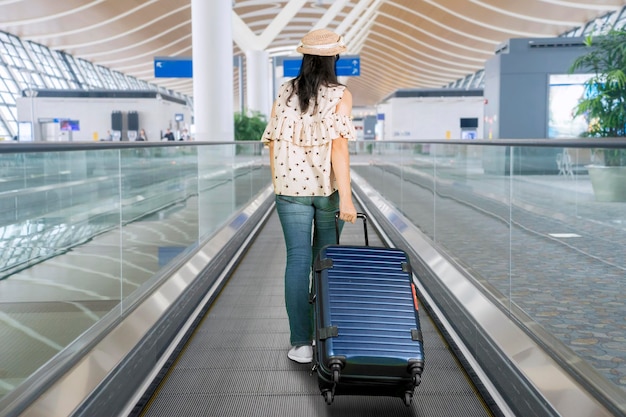 Vrouw lopen op de roltrap van de luchthaven met bagage