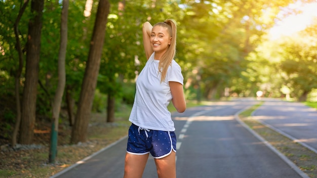 Vrouw loper armen strekken voordat zomer park ochtend Middelbare leeftijd atletische vrouwelijke warming-up lichaam voordat u loopt