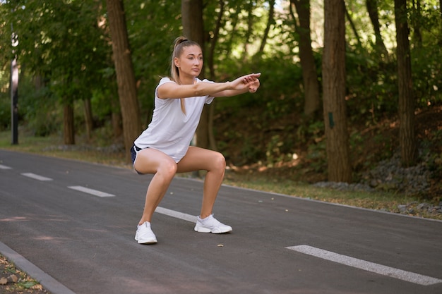 Vrouw loper benen strekken voordat u zomer park ochtend uitoefent