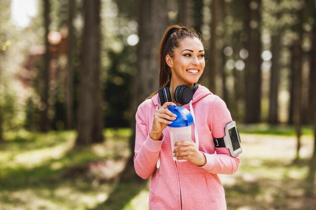 Vrouw loper drinkt water en neemt een pauze na het joggen in de buitenlucht