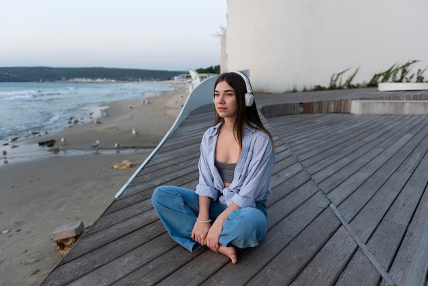 Foto vrouw luisteren naar muziek naast het strand