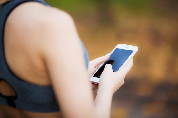 Vrouw luistert naar muziek op de telefoon terwijl ze buiten aan het sporten is