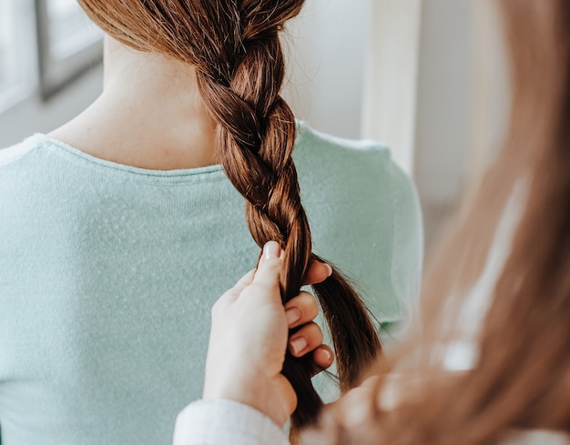 Vrouw maakt een vlecht voor haar vriend