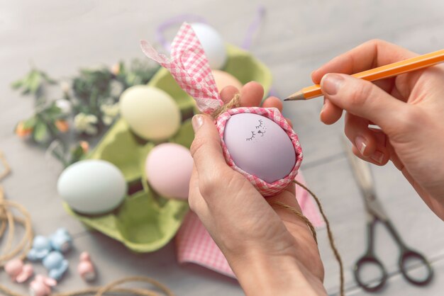 Vrouw maakt leuke decoratieve eieren voor paasvakantie. doe-het-zelf Pasen geschenken concept. schattige pastelkleurige eieren