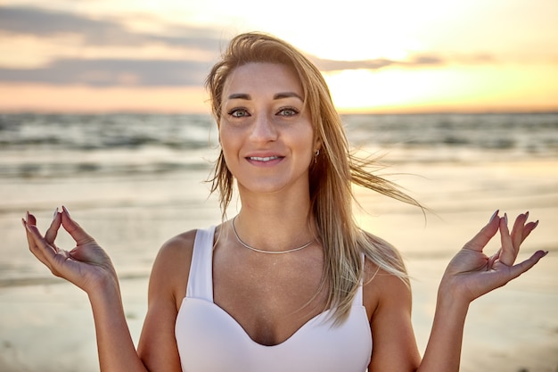 Vrouw maakt 's avonds yoga-training aan zee