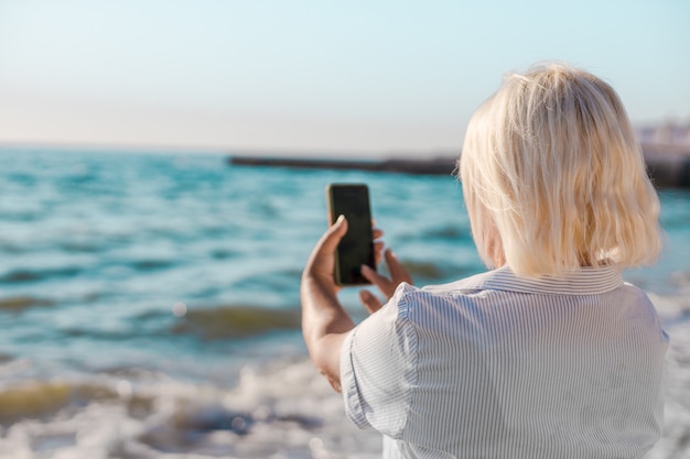 Vrouw maakt selfie foto door smartphone van de zee