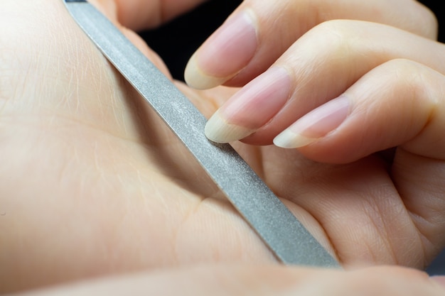 Vrouw maakt thuis een manicure, knipt haar nagels. detailopname. nagels knippen proces. nagelvijl macro.