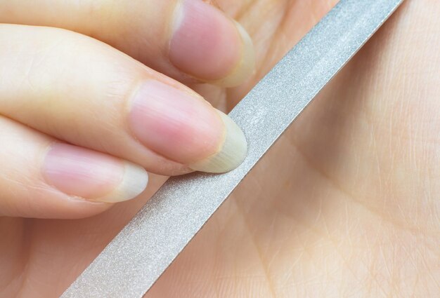 Vrouw maakt thuis een manicure, knipt haar nagels. Detailopname. Nagels knippen proces. Nagelvijl macro.