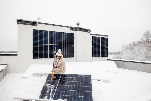 Vrouw maakt zonnepanelen schoon van sneeuw