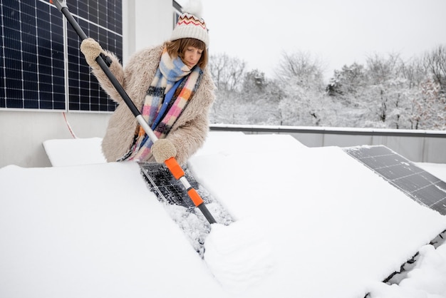Vrouw maakt zonnepanelen schoon van sneeuw