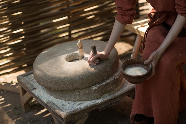 Vrouw maalt tarwe en maakt meel op molensteen