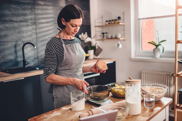 Vrouw maatregel bloem op keukenweegschaal