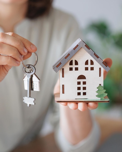 Vrouw makelaar of hypotheekagent houdt een miniatuur van het huis en sleutels in haar handen verkoop en