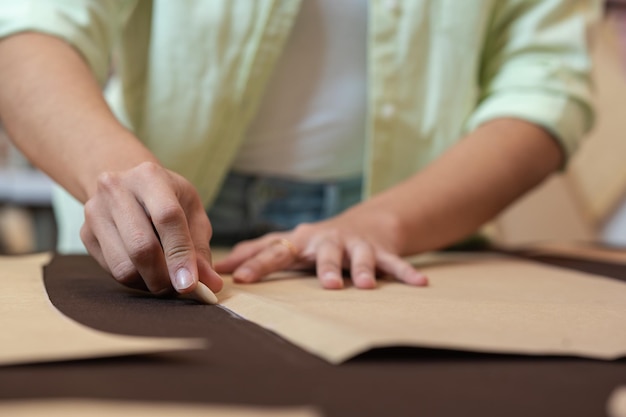 Vrouw markeert met krijt een kledingstuk om uit te knippen in een naaiatelier