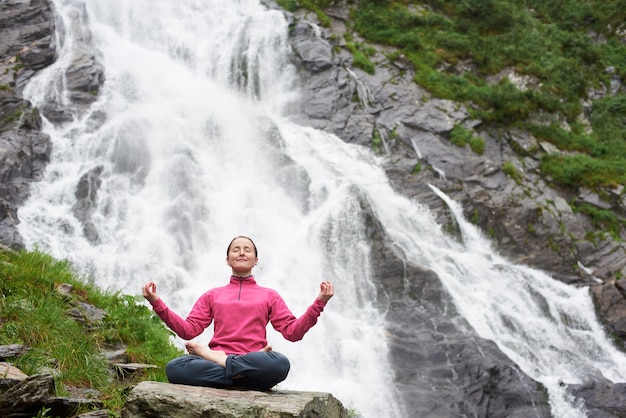 Vrouw mediteren in de buurt van waterval