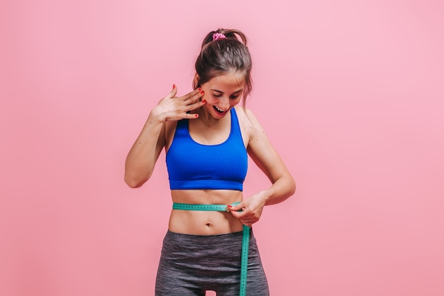 Vrouw meet een taille op een roze muur