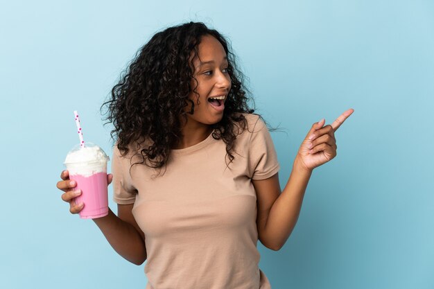 Vrouw met aardbei milkshake geïsoleerd op blauw met de bedoeling om de oplossing te realiseren terwijl het opheffen van een vinger