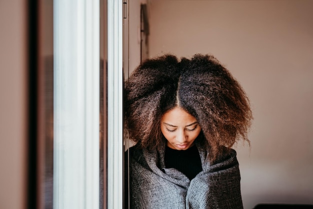 Vrouw met afro haar kijkt naar beneden door het raam