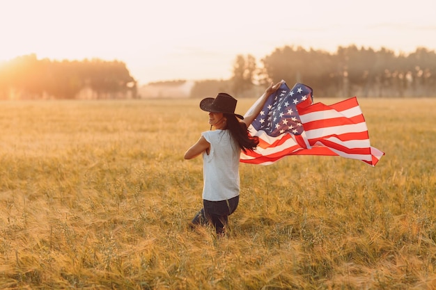 Vrouw met Amerikaanse vlag op het veld bij zonsondergang Labor Day concept