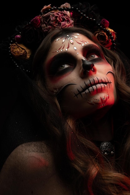 Vrouw met artistieke griezelige make-up en verse bloemen op het hoofd staande voorbereid op halloween-feest