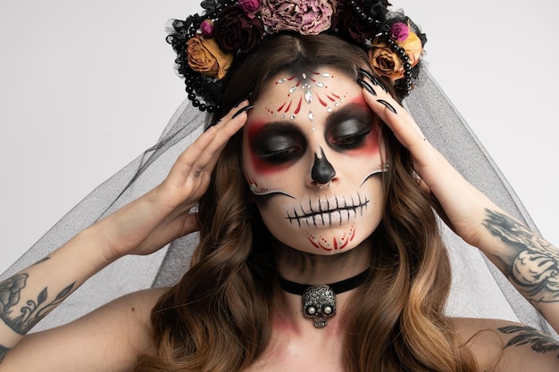 Vrouw met artistieke griezelige make-up en verse bloemen op het hoofd staande voorbereid op halloween