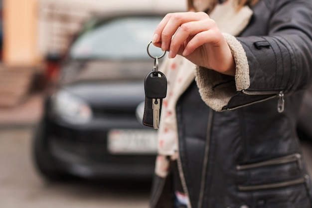 vrouw met autosleutels voor een auto