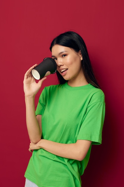 Vrouw met Aziatische verschijning in een groen t-shirt een glas drank plezier geïsoleerde achtergrond ongewijzigd