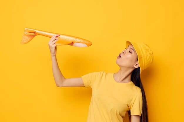 Vrouw met Aziatische verschijning met een geel vliegtuig in zijn handen een stuk speelgoed geïsoleerde achtergrond ongewijzigd