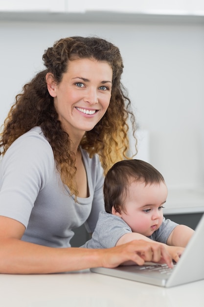 Vrouw met baby die laptop met behulp van