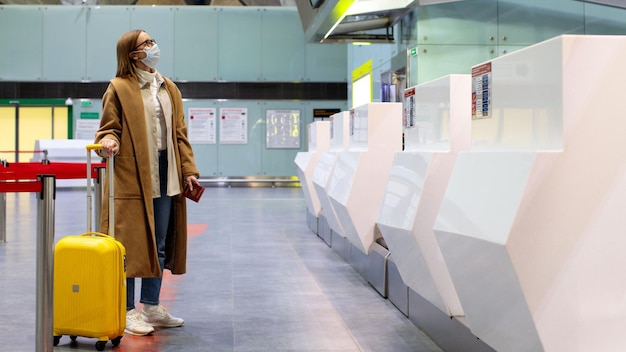Vrouw met bagage die wacht bij de check-in van de luchthaven