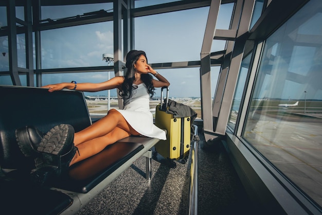 Foto vrouw met bagage zit in het vertrekgebied van de luchthaven