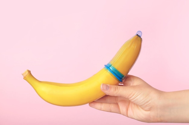Vrouw met banaan met condoom tegen kleur achtergrond Veilig seks concept