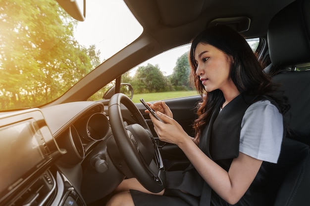 Vrouw met behulp van een smartphone in een auto