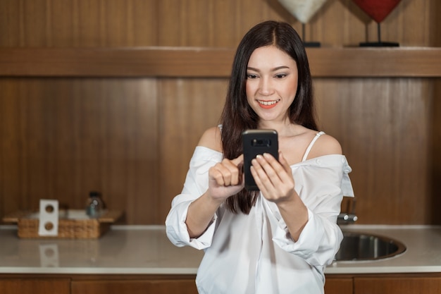 vrouw met behulp van haar smartphone in de keuken kamer