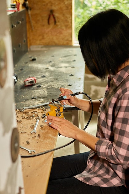 Vrouw met behulp van kracht werkende slijpmachine vrouwelijke hand maalt een metalen noten