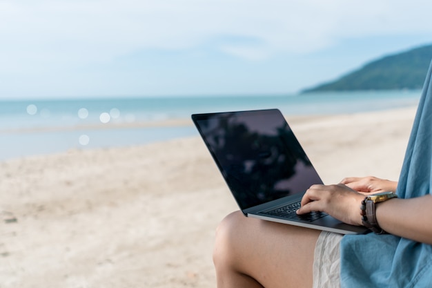 Vrouw met behulp van laptop en smartphone om te studeren in vakantie cady op strand achtergrond.