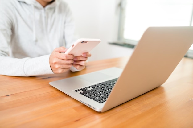 Vrouw met behulp van laptopcomputer en mobiele telefoon thuis